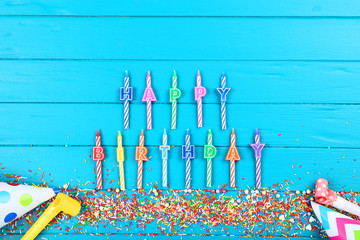 Happy Birthday candles with sprinkles on blue wooden table