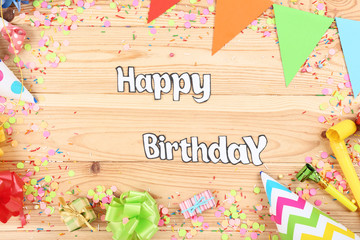 Text Happy Birthday with party decorations on wooden table