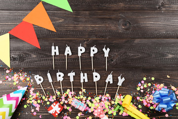 Happy Birthday candles with party decorations on wooden table