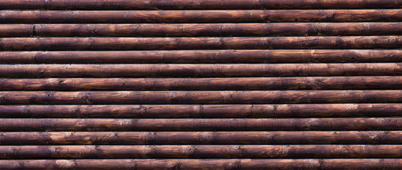 Dark treated logs lying on top of each other