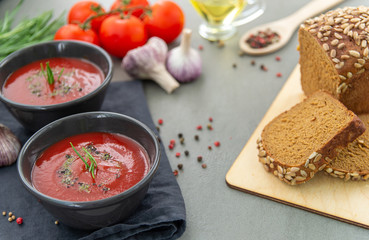 Cold tomato gazpacho soup in a deep plate on a stone background. Traditional Spanish cuisine. The concept of Spanish cold soup of ripe tomatoes.