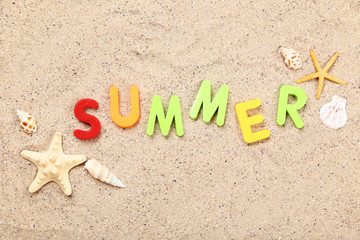 Word Summer with seashells on beach sand