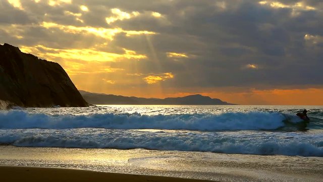 Golden sunset with sun's rays over the ocean. Itzurun beach, flysch of Zumaia on the coast of Gipuzkoa, Spain. Outdoor fitness lifestyle.