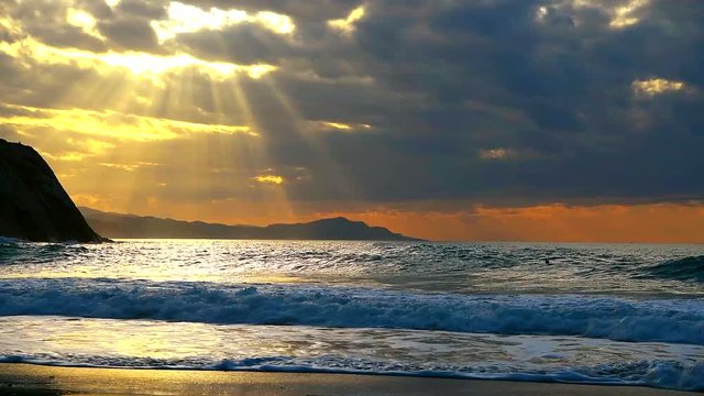 Golden sunset with sun's rays over the ocean. Itzurun beach, flysch of Zumaia on the coast of Gipuzkoa, Spain. Outdoor fitness lifestyle.