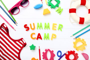 Text Summer camp with toys, pencils and t-shirt on white wooden table