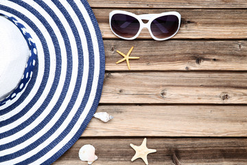 Beach hat with seashells and sunglasses on brown wooden table