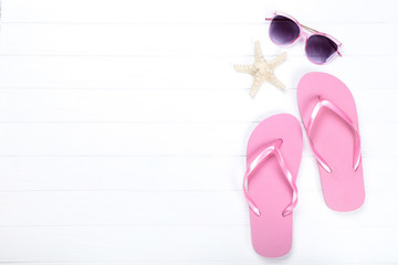 Pair of flip flops with starfish and sunglasses on white wooden table
