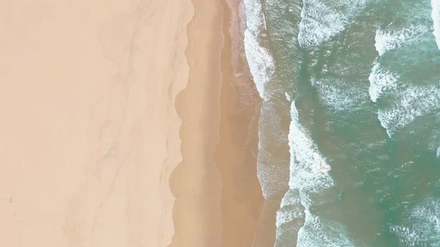 Aerial Drone motion View Of Atlantic Ocean Waves Crashing Over A Sandy beach on Portugal coastline