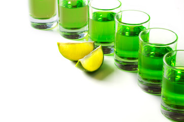 Absinthe green liquor in glasses. Alcoholic hallucinogenic beverage. White background. Pieces of...