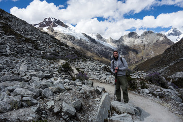 Backpacker with hiking poles standing in front of the snow-covered mountain range on the hiking trail Laguna 69, Huascaran National Park, Peru