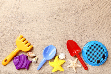 Fototapeta na wymiar Colorful plastic toys and seashells on beach sand
