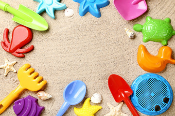 Fototapeta na wymiar Colorful plastic toys and seashells on beach sand