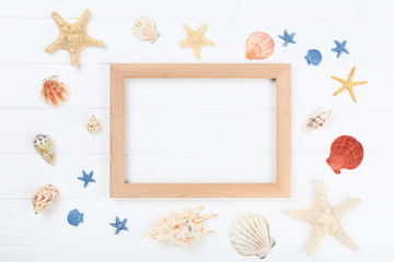 Fototapeta na wymiar Wooden blank frame with seashells on white table