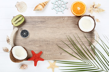 Wooden blank frame with seashells and fruits on white table