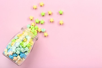 Fototapeta na wymiar Colorful paper stars in glass jar on pink background