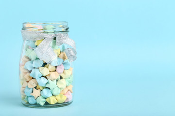 Colorful paper stars in glass jar on blue background