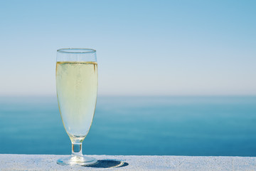 Glass of white dry wine over seaside background, summertime.