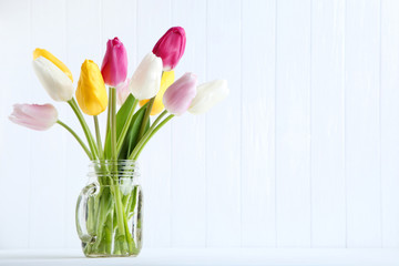 Bouquet of tulip flowers in glass jar on white background