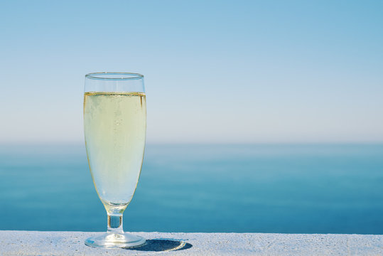 Glass of white dry wine over seaside background, summertime.