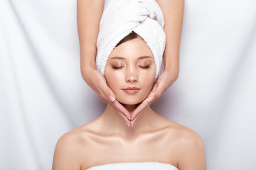 pretty woman in bath towel on her head receiving facial massage, beauty theraphy after bath, spa treatment for females