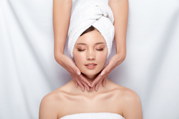 beautician massaging neck of woman in bath towel and with naked shoulders, facial procedures in spa for pretty girl