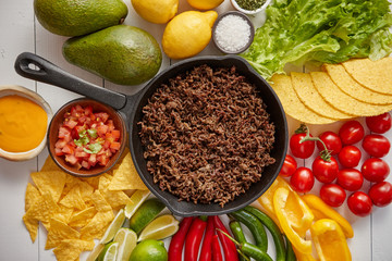 Ingredients for Chili con carne in frying iron pan on white wooden table