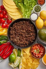 Ingredients for Chili con carne in frying iron pan on white wooden table