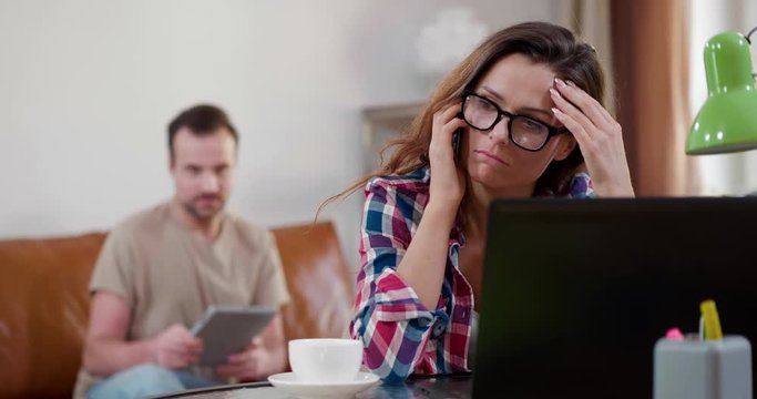 Young depressed woman disagrees with interlocutor during important call, hangs up. Her husband tries to support her