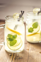 Cold Fresh Mojito Cocktail Lemonade with Ice, Lemon and Mint Leaves in Mason Jar on Rustic Dark Wooden Background. Summer Concept.