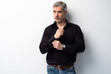 Fototapeta premium Cheerful man of middle age against white background, wearing jeans and black shirt, mid shot.