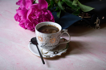 A cup of coffee, peonies and female bag.