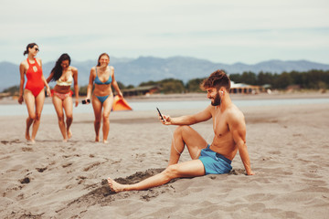 Fototapeta premium Handsome man on the beach listens to music over the earphones