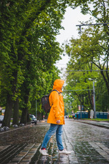 Fototapeta na wymiar man crossing street in yellow raincoat. overcast weather
