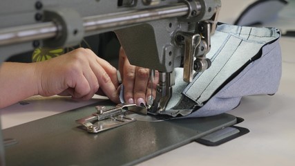 Tailor sews black leather in sewing workshop. needle of sewing machine in motion. process of sewing leather goods. two needles of the sewing machine quickly moves up and down, close-up.