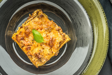 Italian Lasagne with Minced Beef and Green Basil on Dark Plate