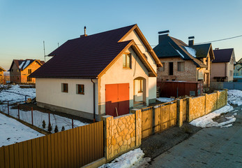 Fototapeta na wymiar Aerial view of new residential house cottage and attached garage with shingle roof on fenced yard on sunny winter day in modern suburban area. Perfect investment in dream house.