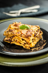 Italian Lasagne with Minced Beef and Green Basil on Dark Plate
