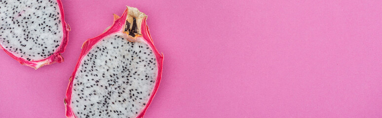 panoramic shot of tropical ripe dragon fruit halves on pink background with copy space