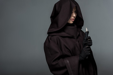 woman in death costume holding burning candle isolated on grey