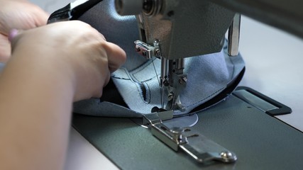 process of sewing leather goods. needle of the sewing machine in motion. two needles of the sewing machine quickly moves up and down, close-up. Tailor sews black leather in a sewing workshop.