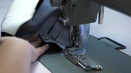 process of sewing leather goods. needle of the sewing machine in motion. two needles of the sewing machine quickly moves up and down, close-up. Tailor sews black leather in a sewing workshop.