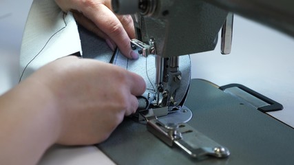 process of sewing leather goods. needle of the sewing machine in motion. two needles of the sewing machine quickly moves up and down, close-up. Tailor sews black leather in a sewing workshop.