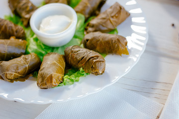 Dolma - rolls made from grape leaves and meat, on white plate.