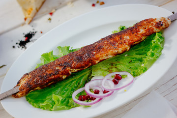 Meat kebab on sckewer, chiken kebab on white plate.