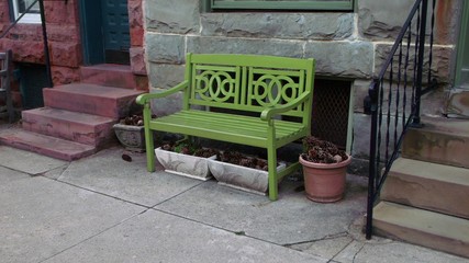 Obraz premium Green bench in front of a rowhouse in Baltimore, Maryland.