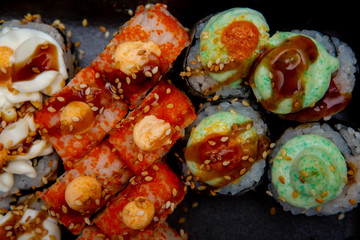 set of different sushi rolls on black background close-up