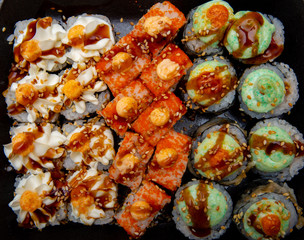 set of different sushi rolls on black background close-up