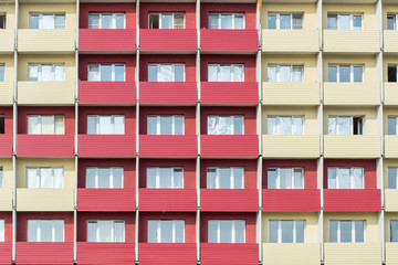 Fototapeta na wymiar The texture of the building. An apartment building red and yellow wall texture with balcony. Architecture background of building walls.