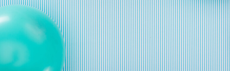 Panoramic shot of blue balloon on striped party background