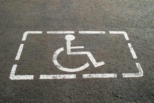 Parking lot with painted sign of wheelchair on asphalt, parking spaces for disabled visitors. Disabled parking spaces. 